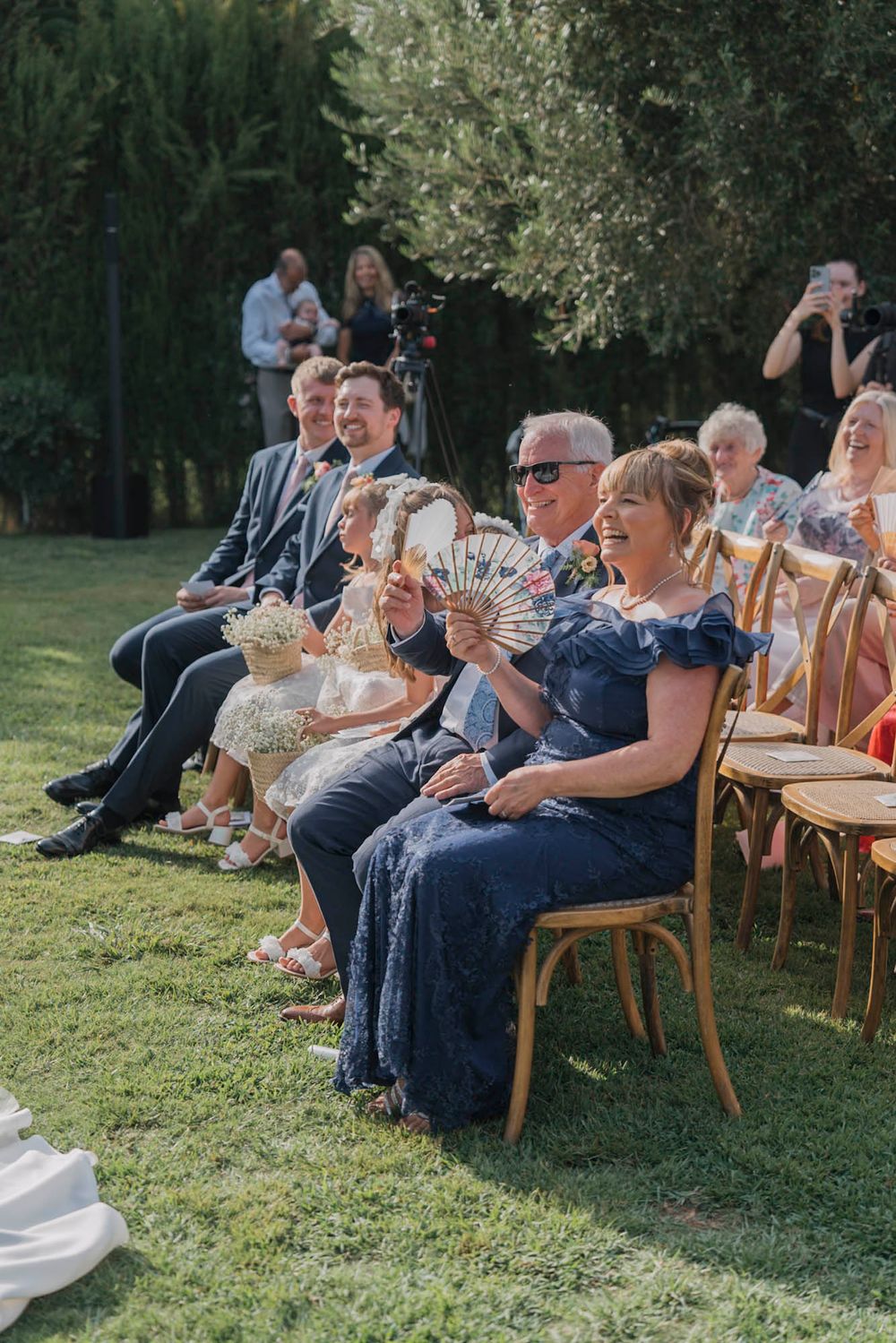 Wedding guests seated on wooden chairs enjoying the outdoor ceremony.