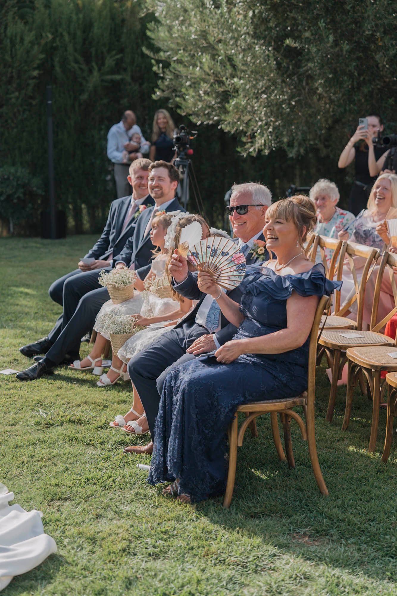 Wedding guests seated on wooden chairs enjoying the outdoor ceremony.