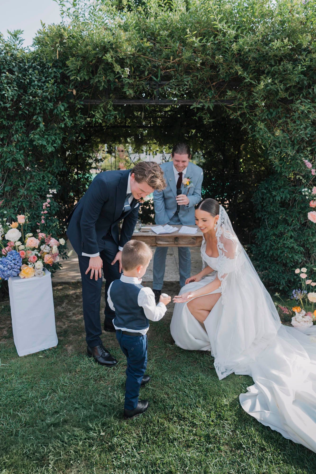 Sweet moment during wedding ceremony with young ring bearer in formal attire.