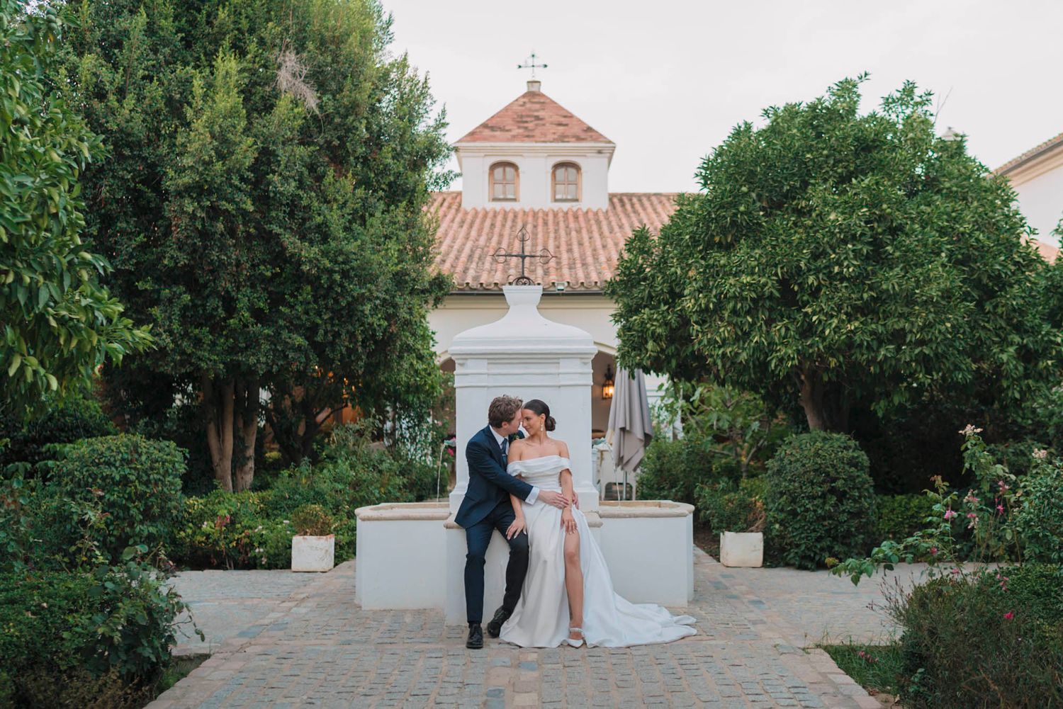 A beautiful wedding scene set against the backdrop of a Spanish colonial church with lush greenery.