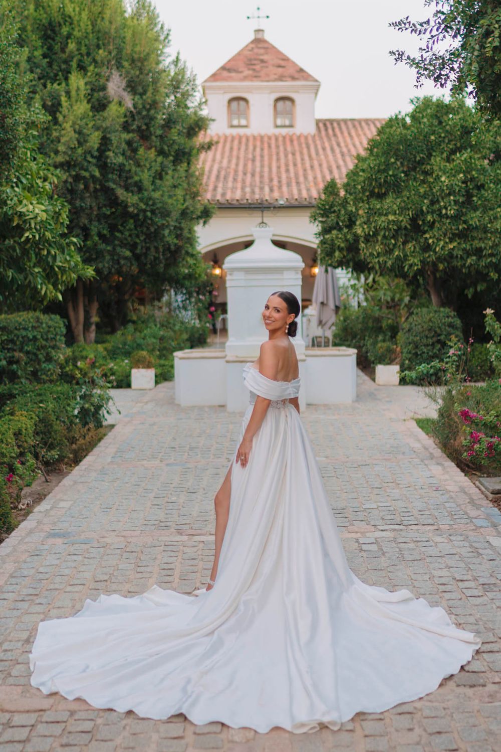 A dramatic wedding dress with long train photographed in front of a Spanish colonial church.