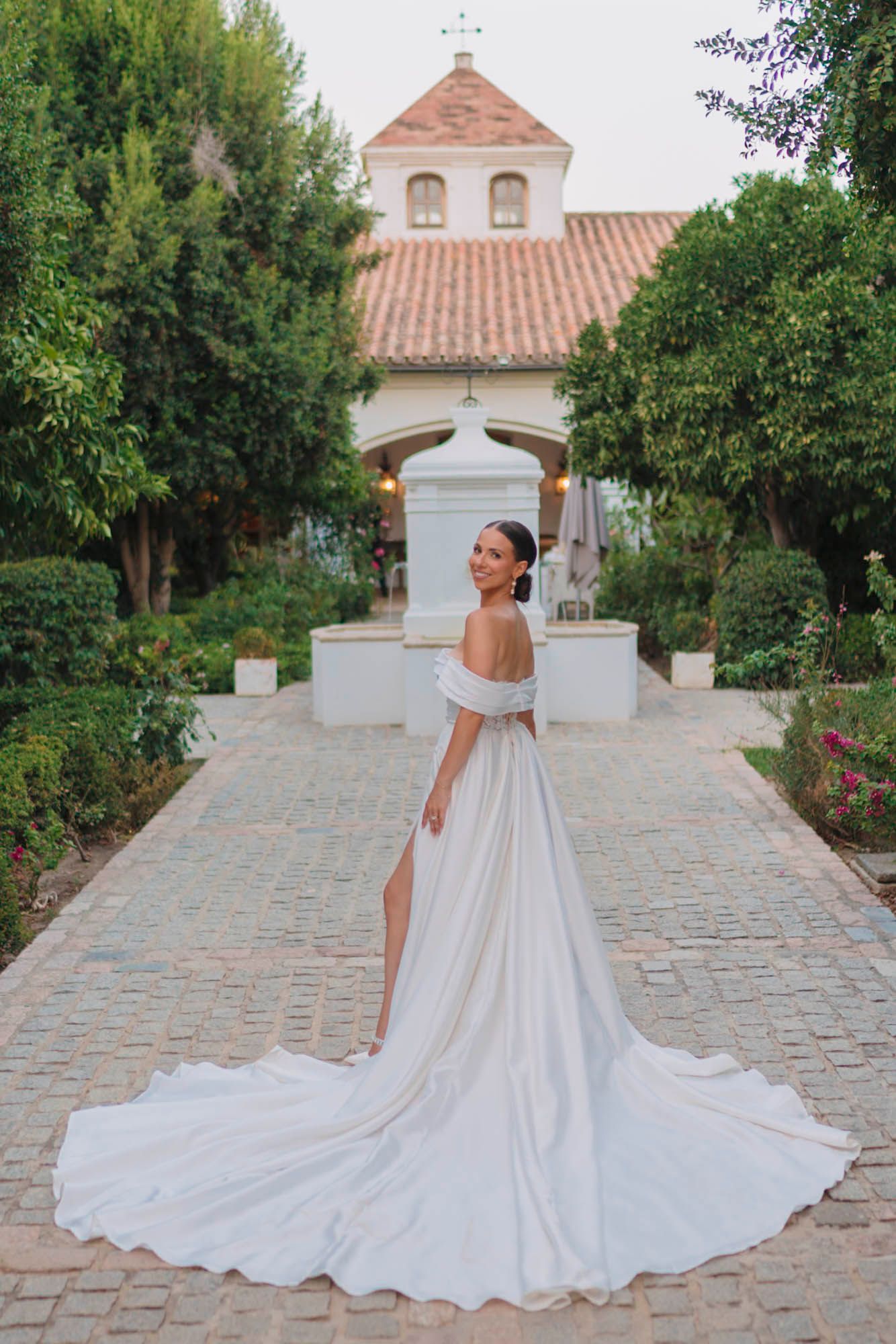 A dramatic wedding dress with long train photographed in front of a Spanish colonial church.