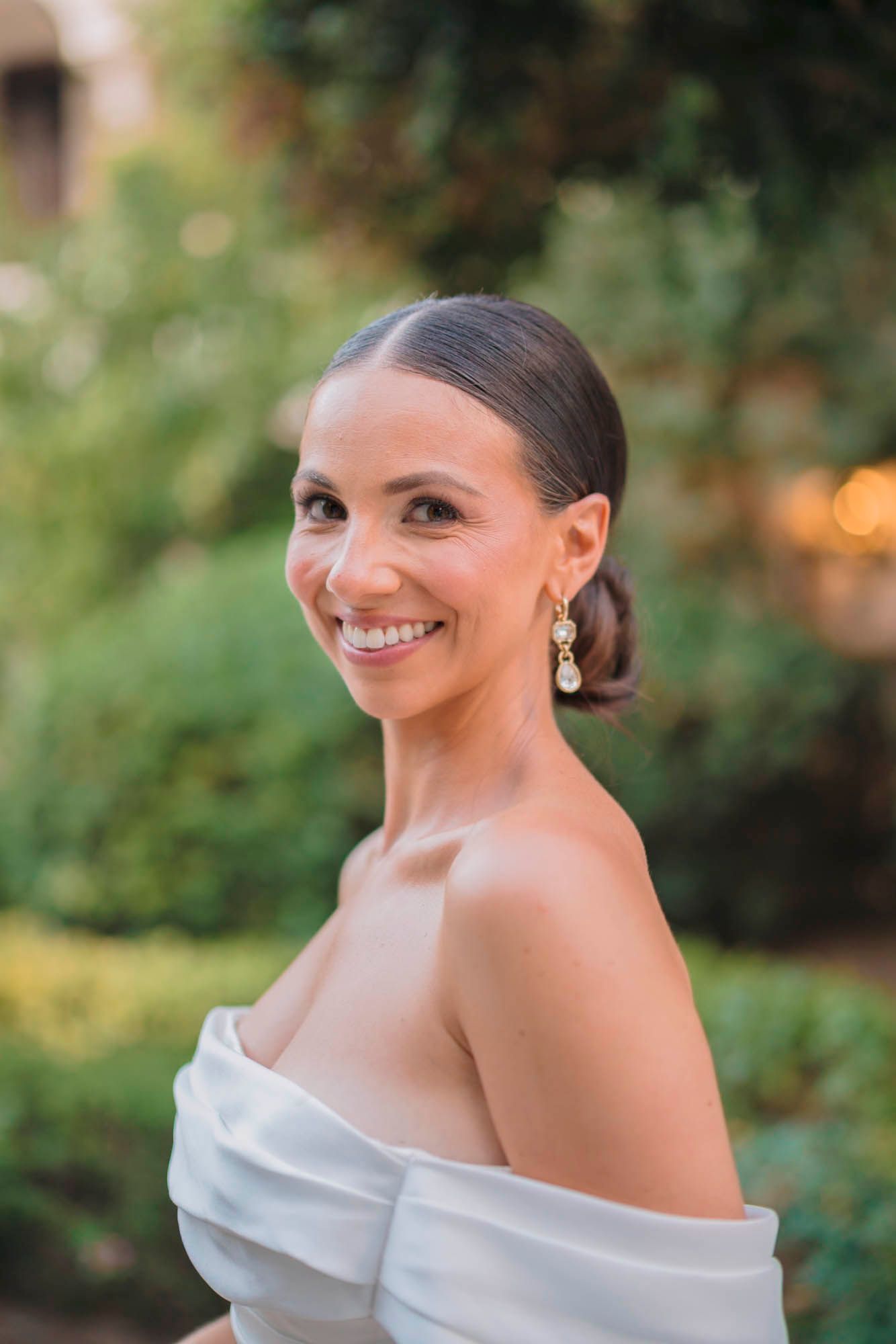 A stunning bridal portrait showcases elegant jewelry and an off-shoulder wedding dress design.