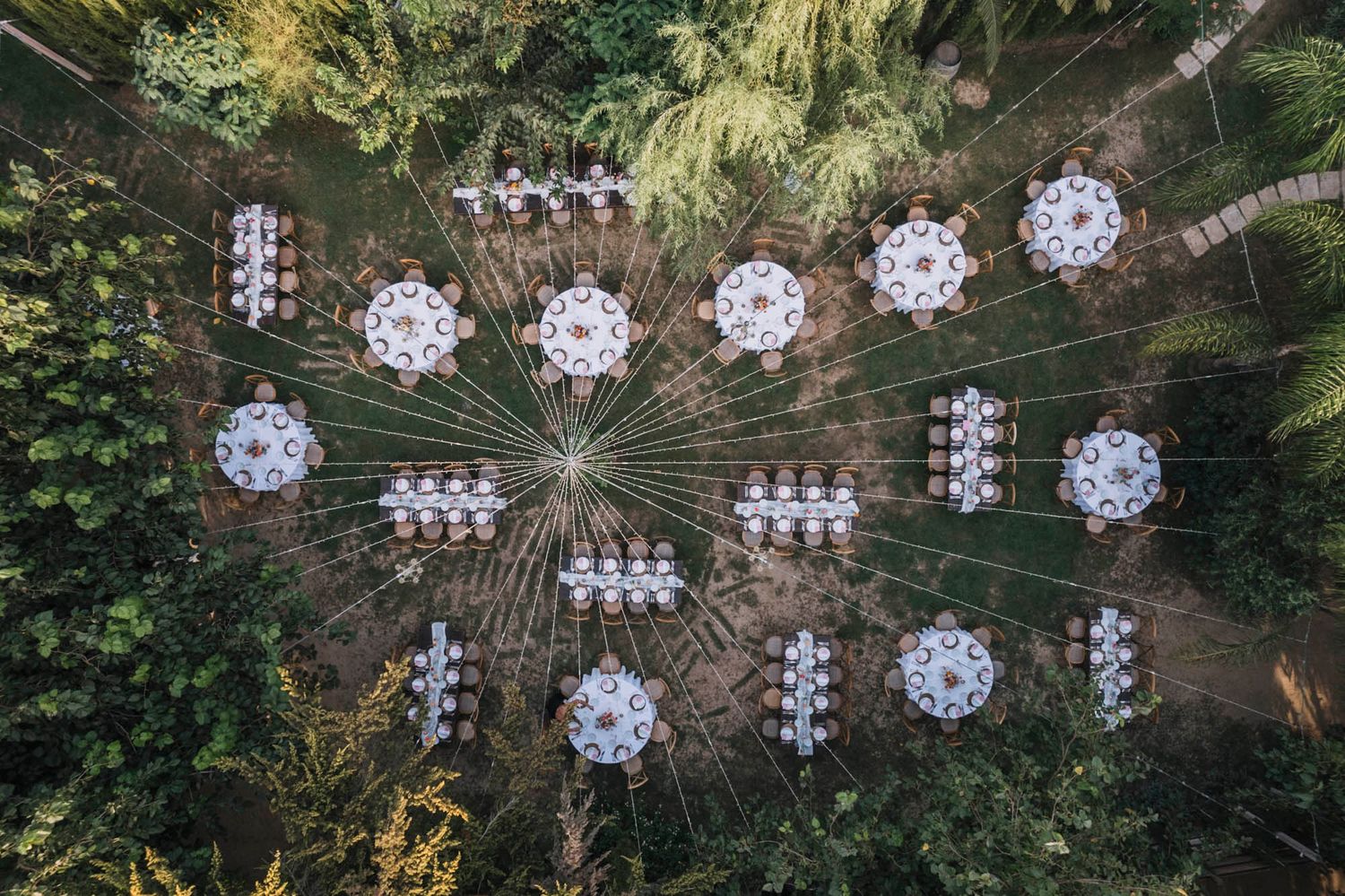 Overhead view of an outdoor wedding reception layout with crystal chandeliers hanging from string lights.