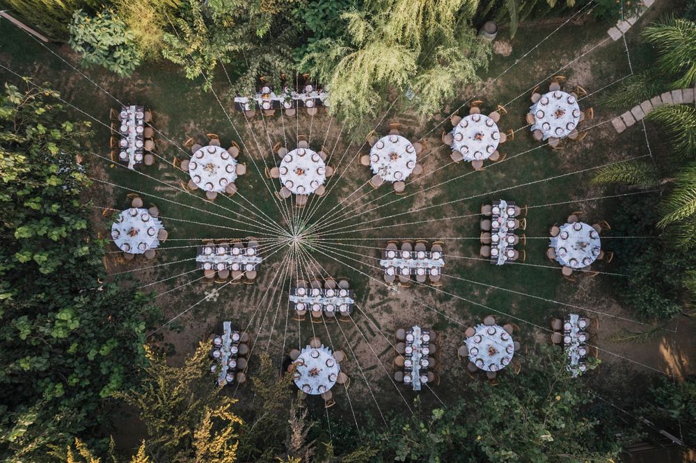 Overhead view of an outdoor wedding reception layout with crystal chandeliers hanging from string lights.