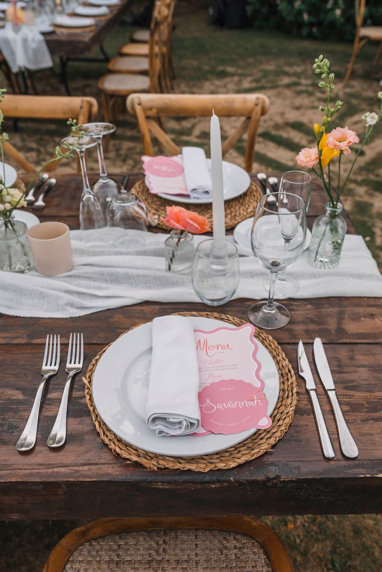 Rustic table setting with woven charger plates, white linens, and delicate floral centerpieces.