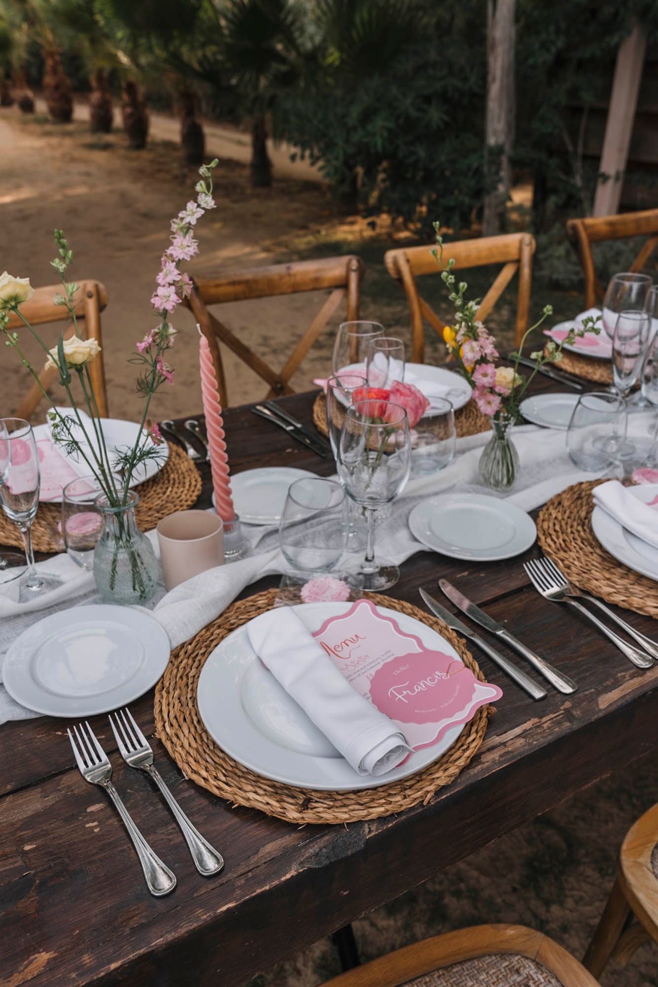 Close-up of rustic wedding place setting with woven charger plate and pink menu card.