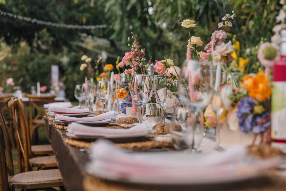 Romantic table setting with delicate floral arrangements and vintage glassware at outdoor reception.