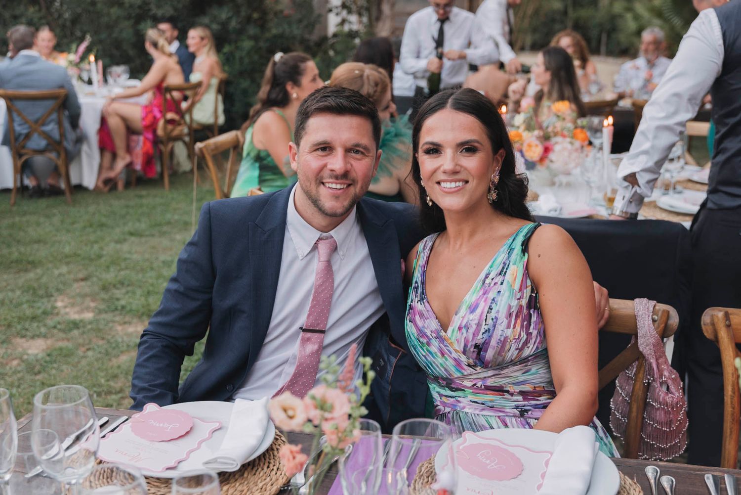 Wedding guests enjoying an elegant outdoor reception dinner at decorated tables.