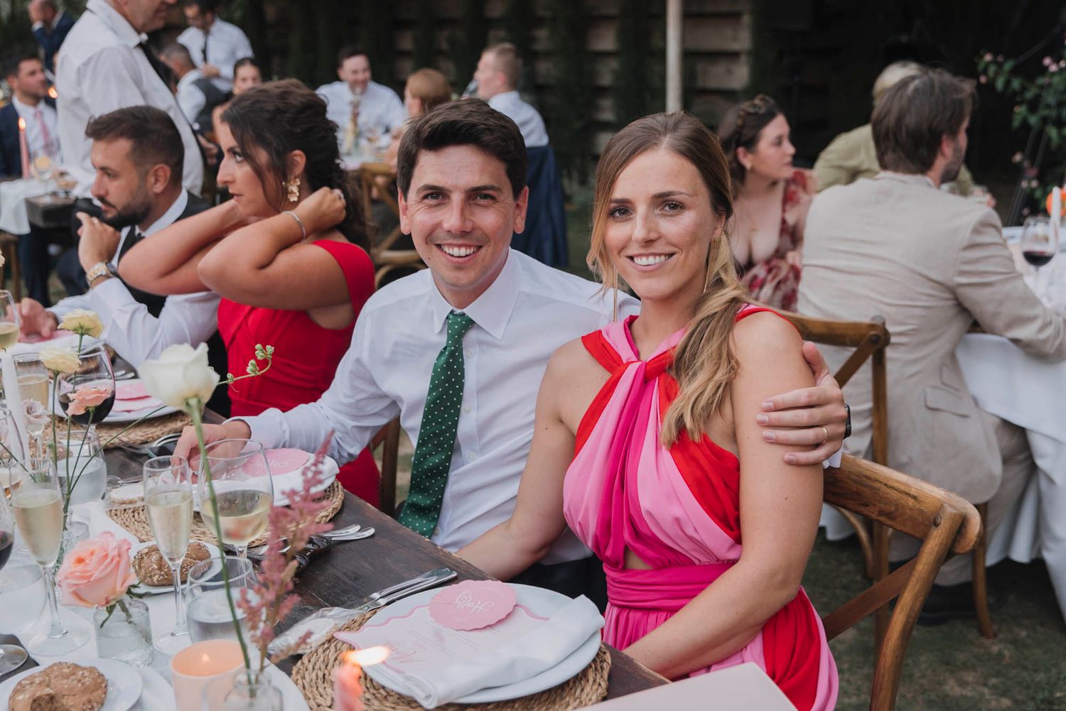 Guests seated at an elegant outdoor wedding reception with festive table decorations.