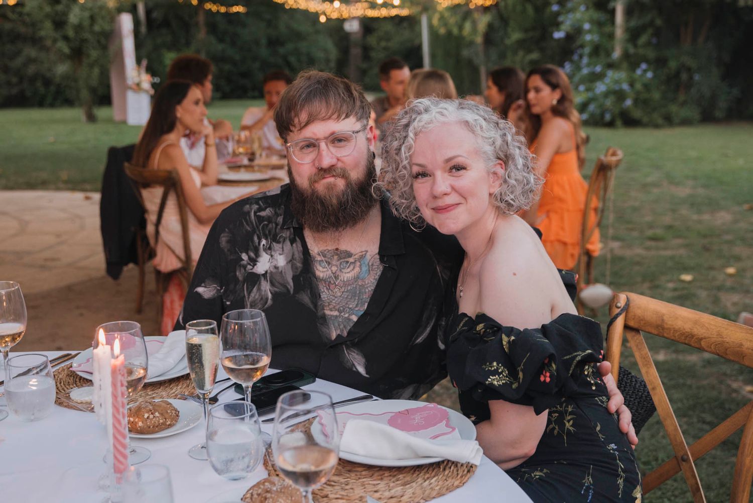 Wedding reception guests enjoying dinner at decorated outdoor tables.