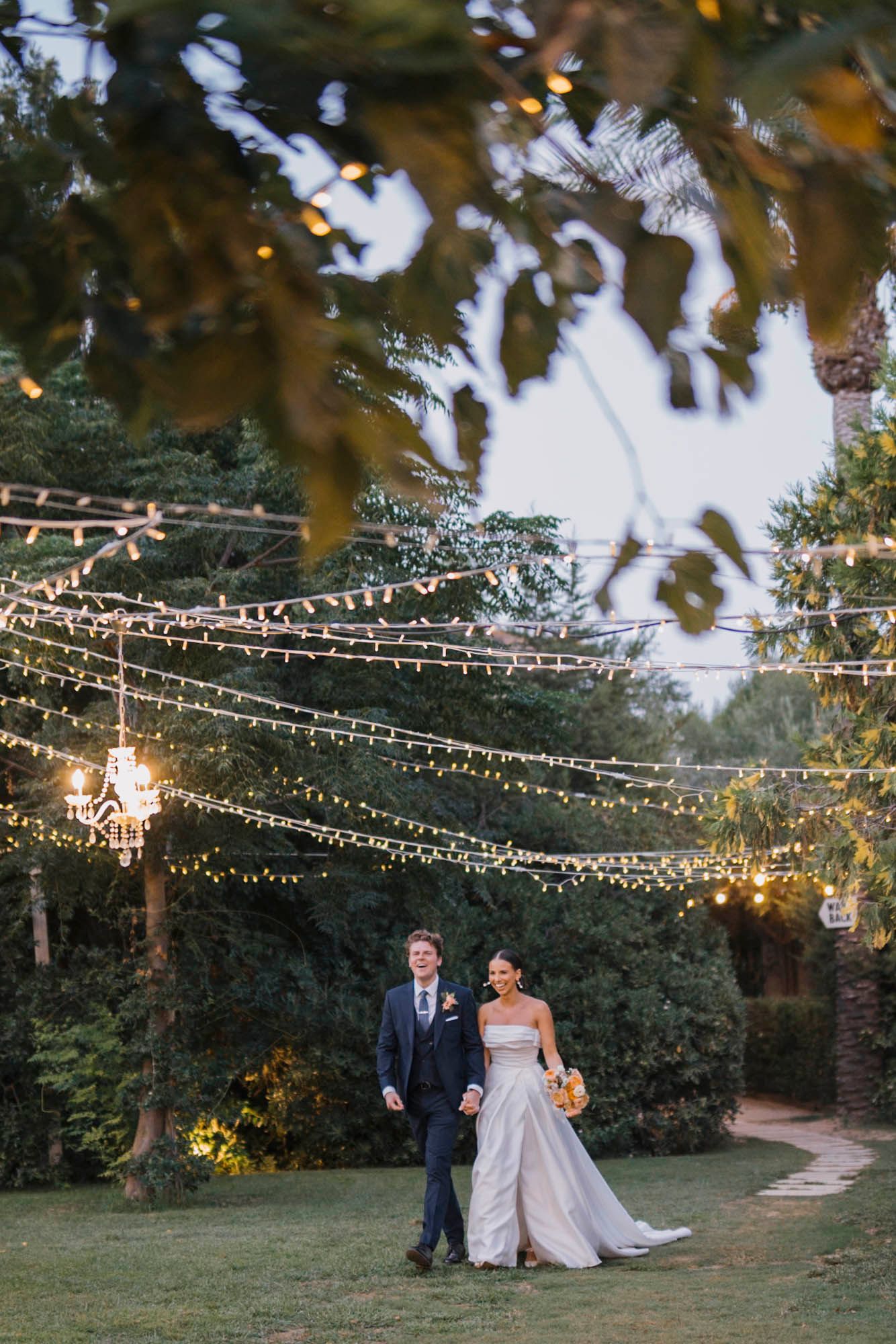 Romantic evening garden wedding scene with string lights creating magical ambiance overhead.