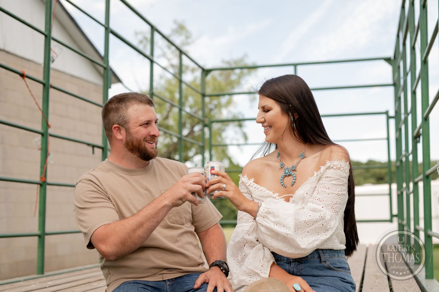 Couple laughing together while sitting on green bleachers during outdoor photo session.
