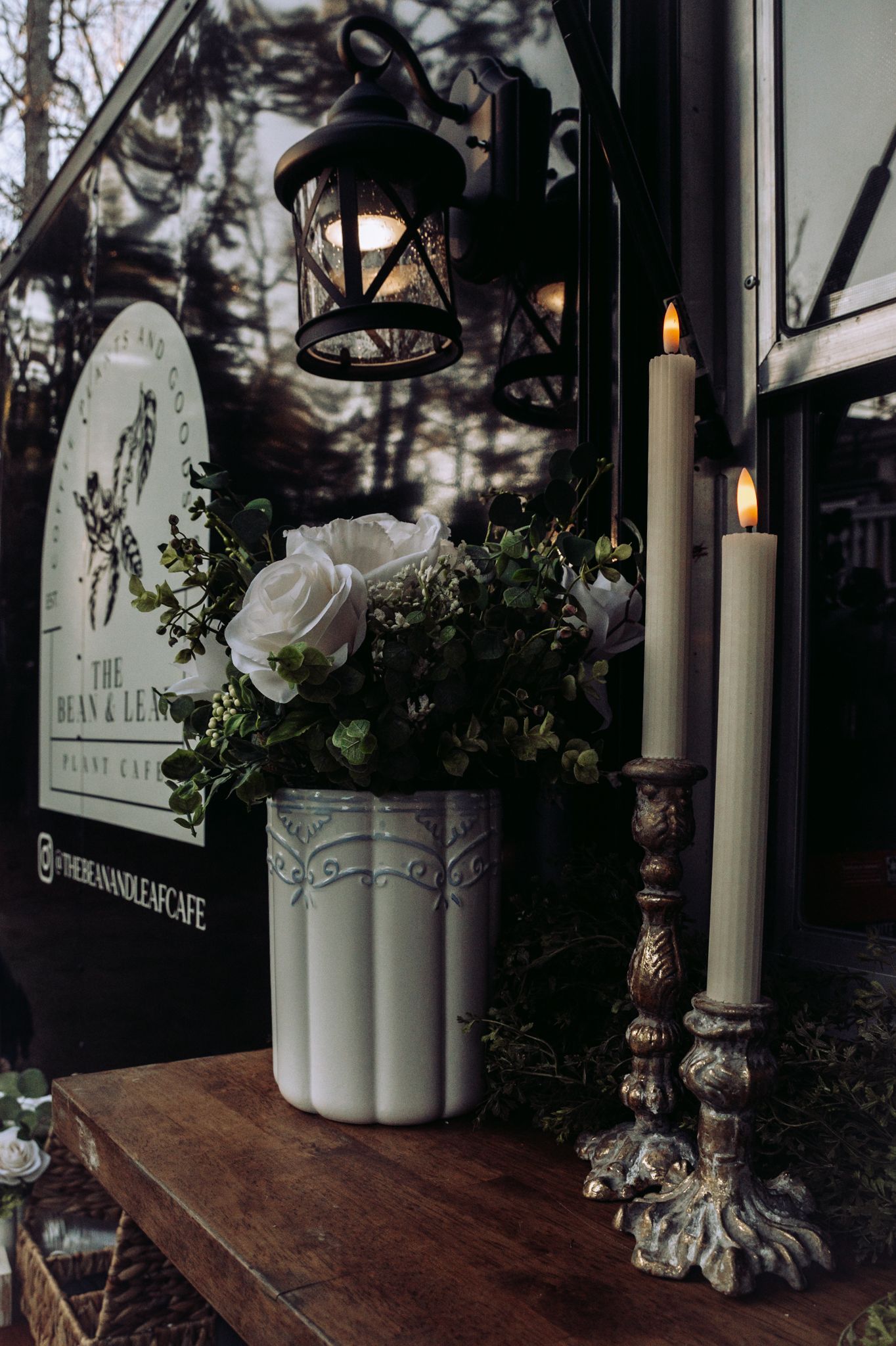 Elegant tabletop display with white roses, candles and lantern at The Bean & Leaf cafe.