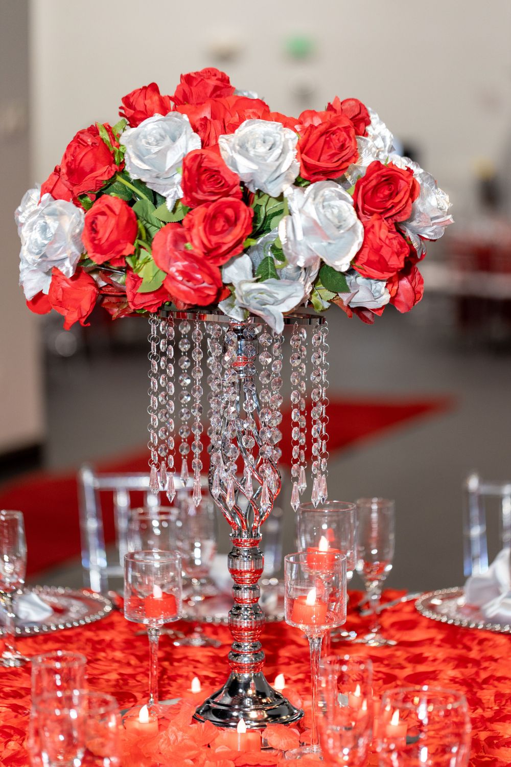 Tall crystal centerpiece with red and white roses on a decorated table setting.