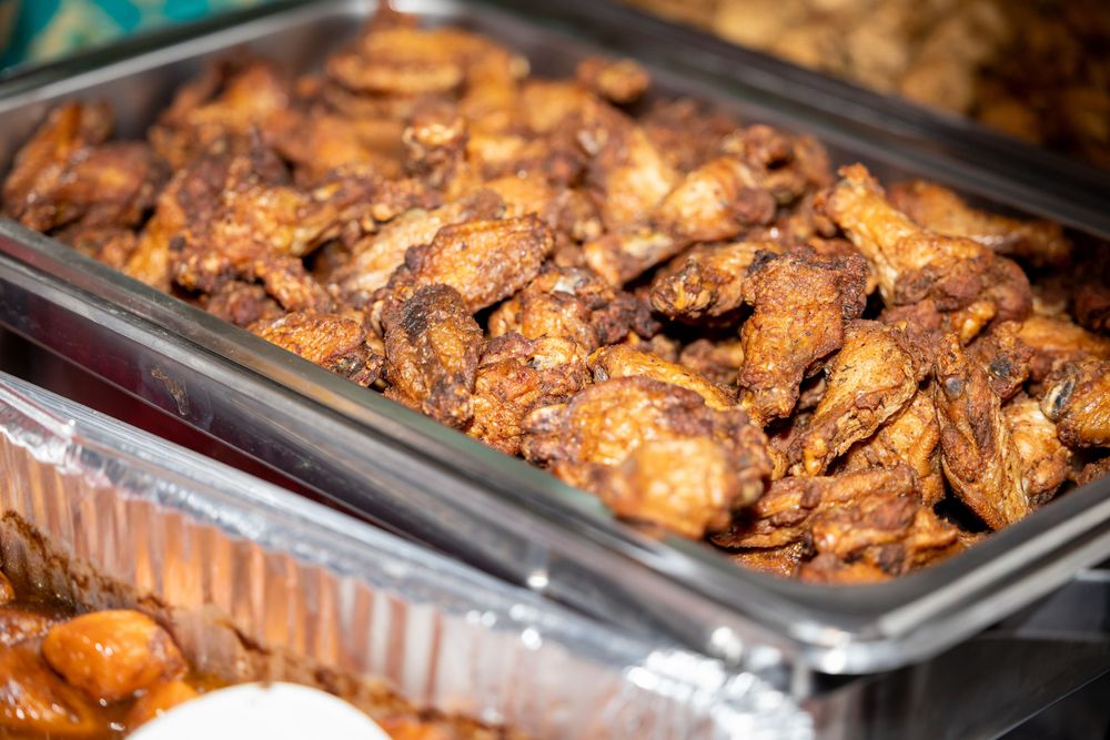Tray of grilled or roasted chicken pieces in catering container.