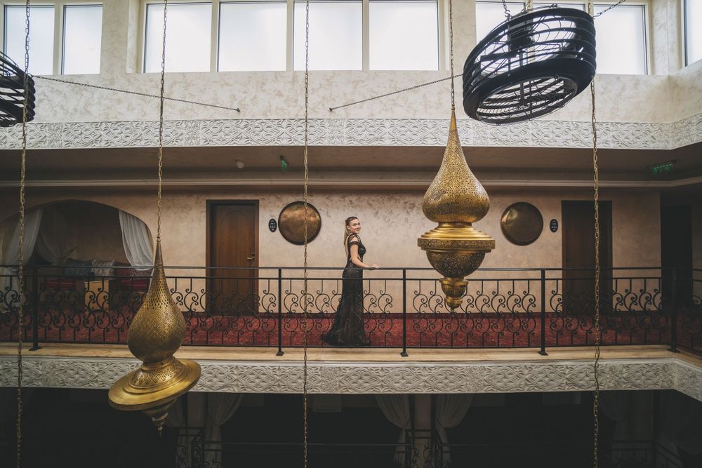 Modern interior with hanging brass pendant lights and ornate balcony railings in atrium space.