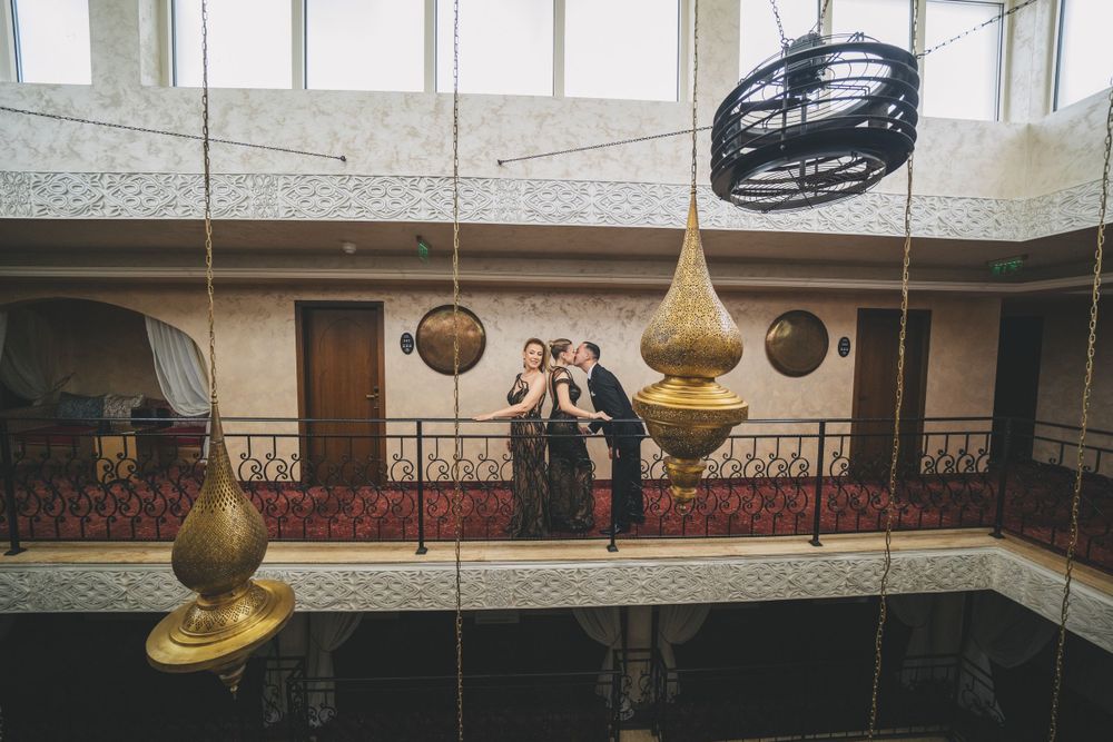 Wide shot of interior architecture showing suspended brass lighting fixtures and decorative balconies.