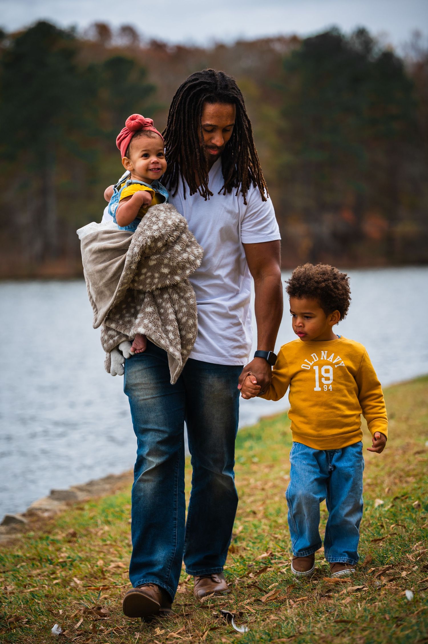 Children play and run through fallen leaves during autumn family photo session.