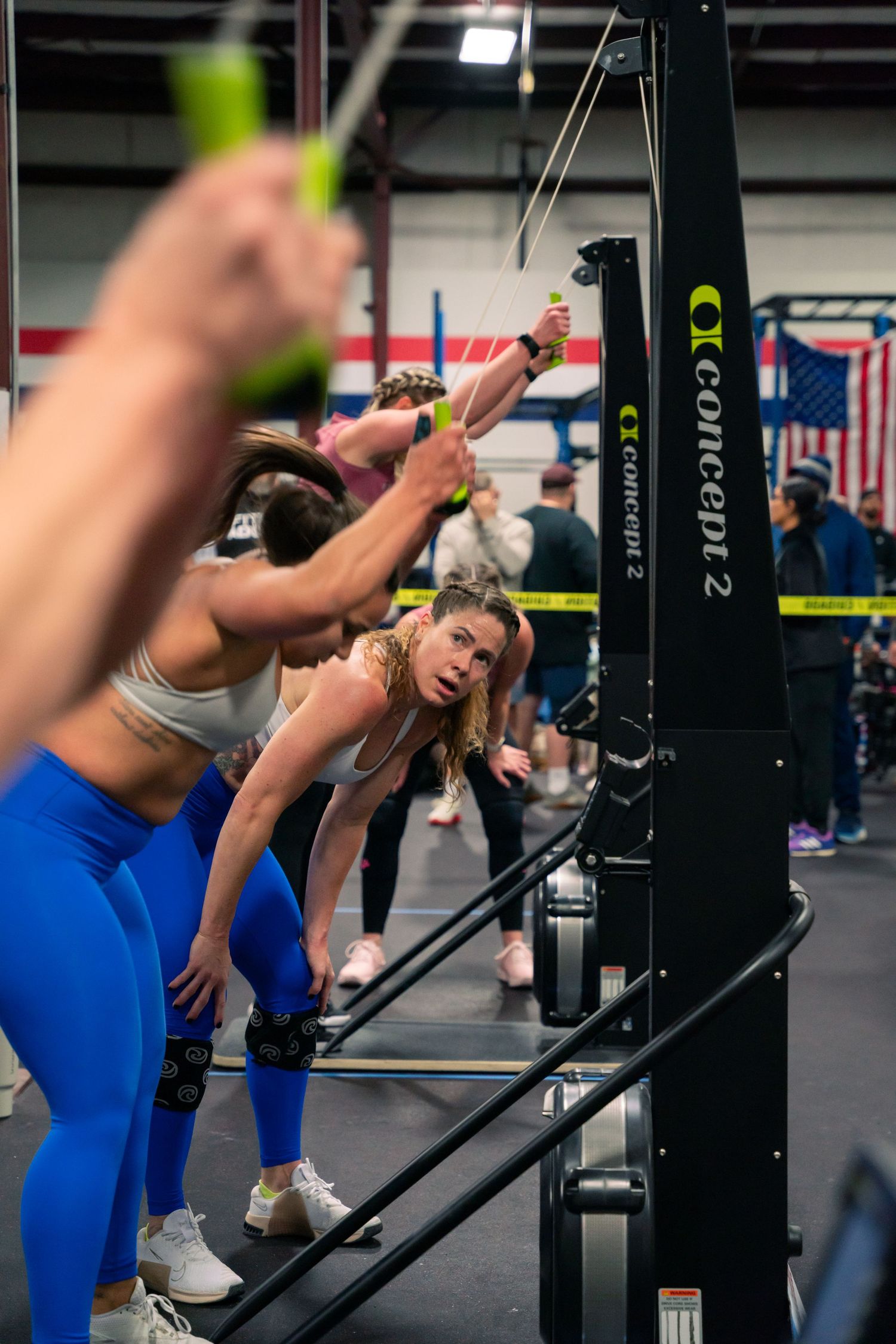 Athletes performing exercises at a CrossFit gym with equipment and American flag in background.