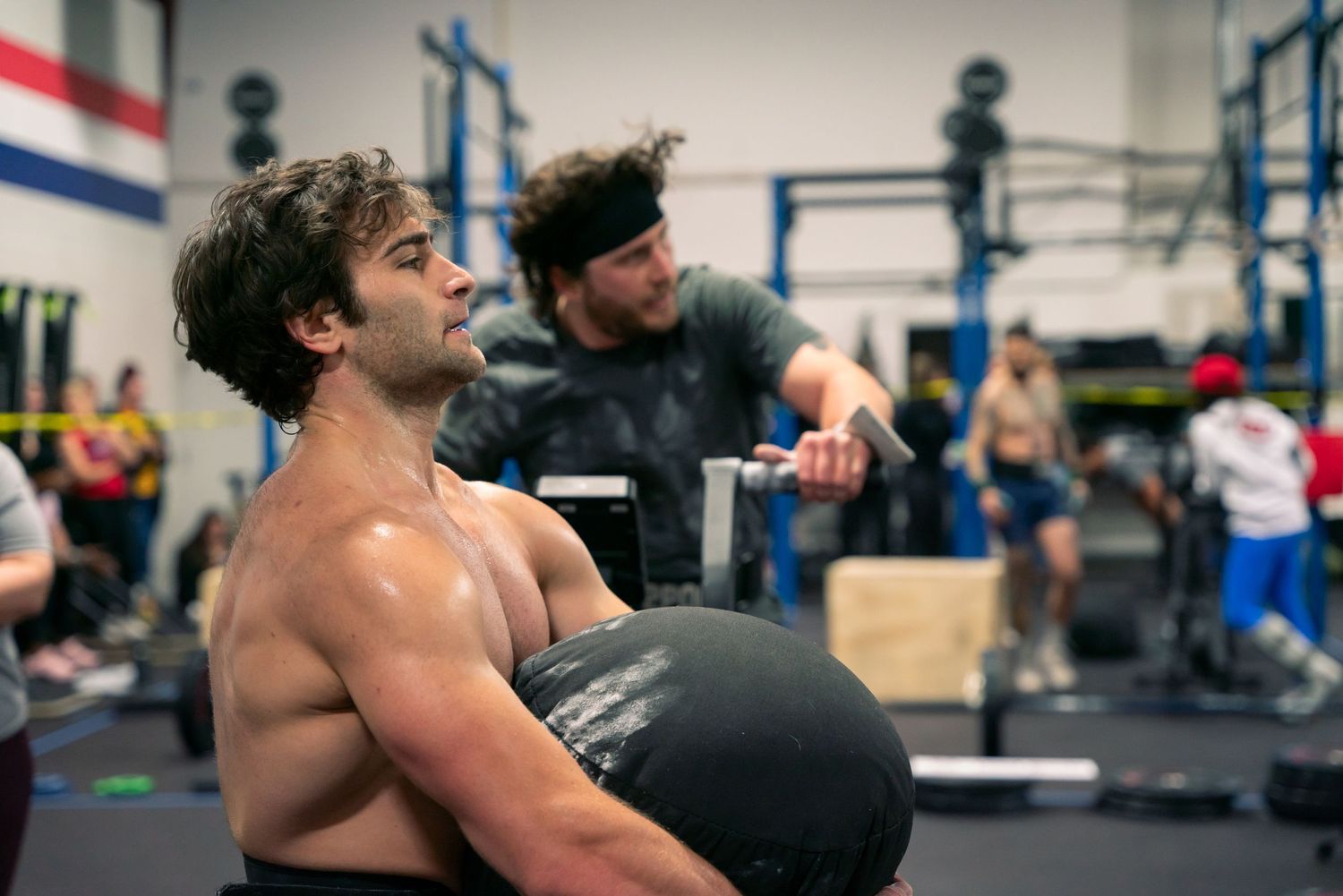 Athlete holding a large medicine ball during an intense CrossFit training session.