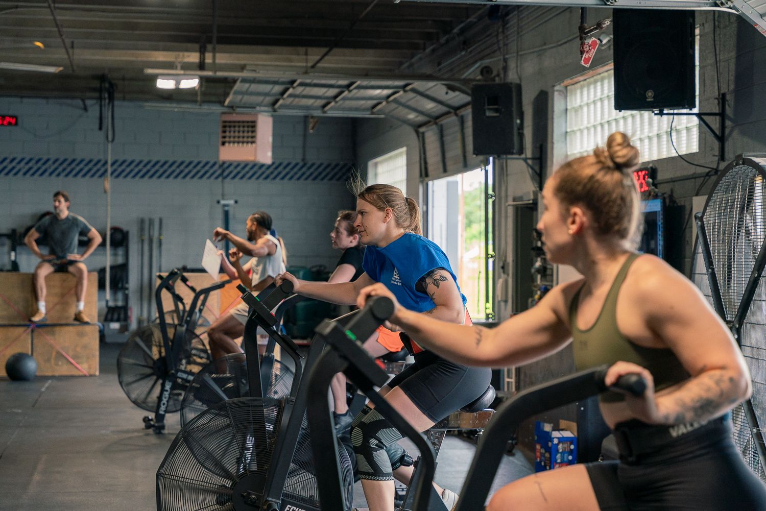 Athletes working out intensely on rowing machines in a crossfit gym during a training session.