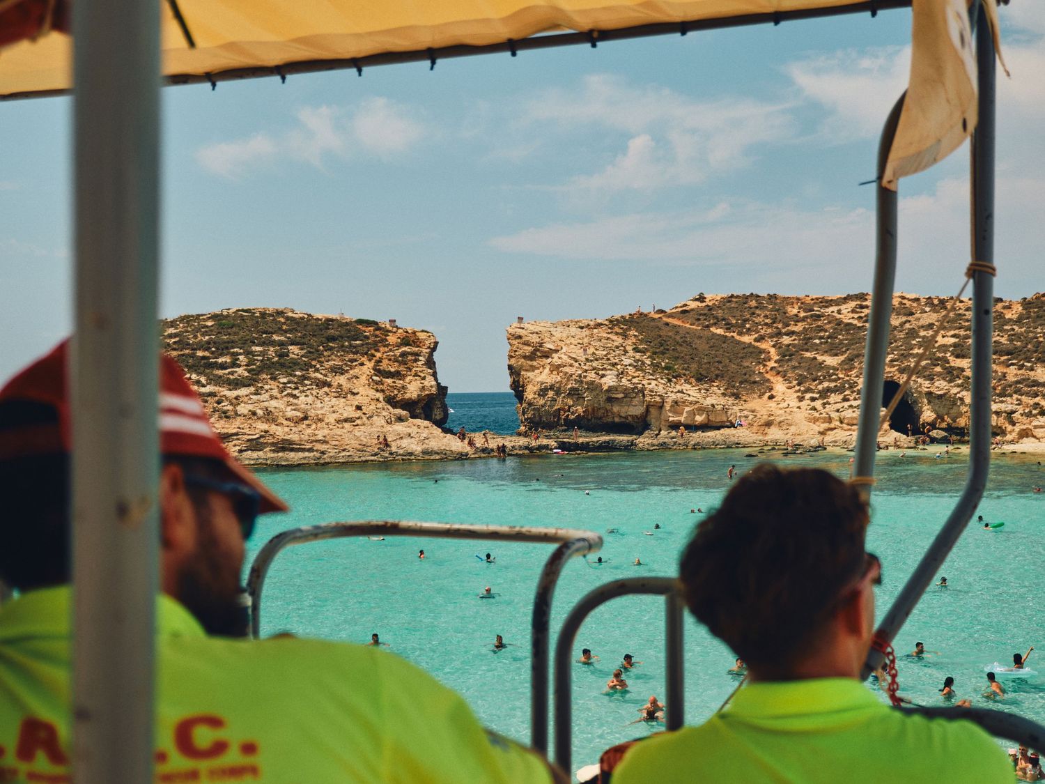 View of Blue Lagoon in Malta with turquoise waters and rocky cliffs seen from life guard crew in neon safety vests.