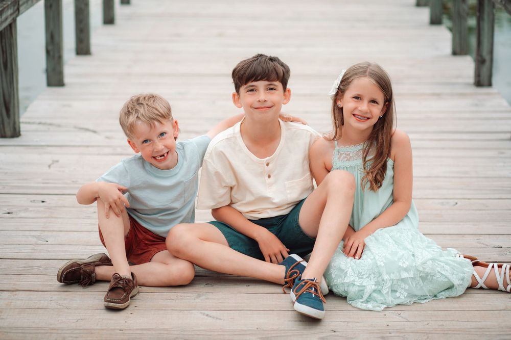 Children lounging casually on a rustic wooden boardwalk during an outdoor photo session.