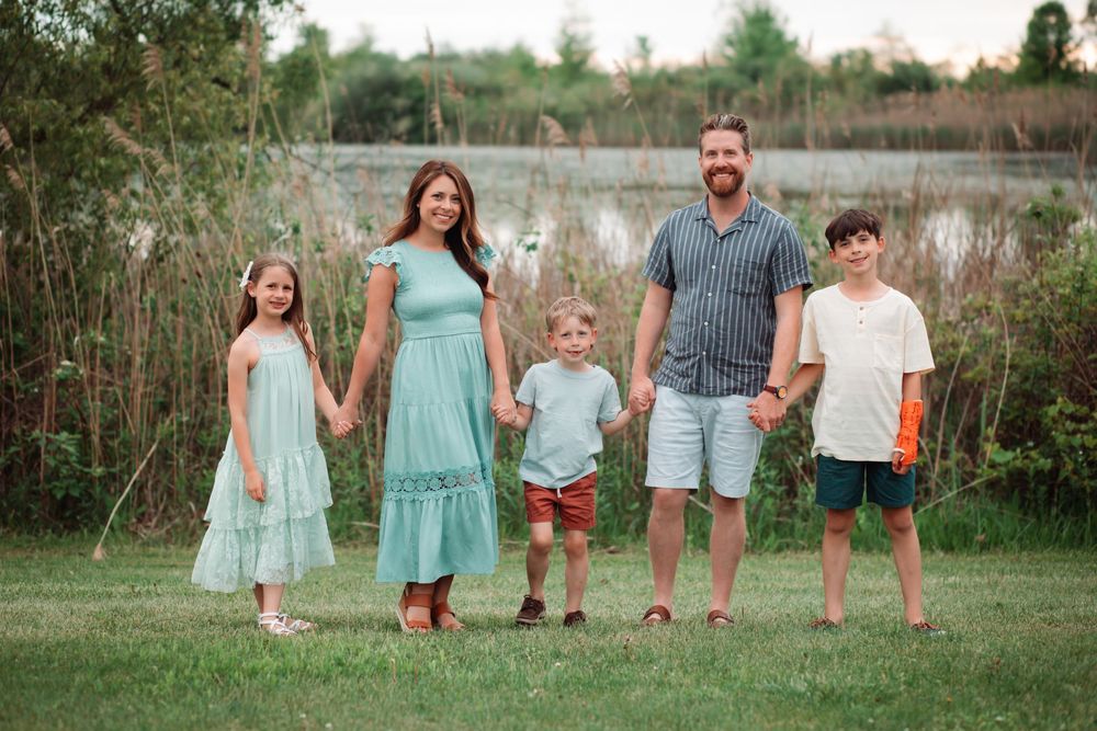Family walking together in coordinated mint and white outfits against a natural outdoor backdrop.