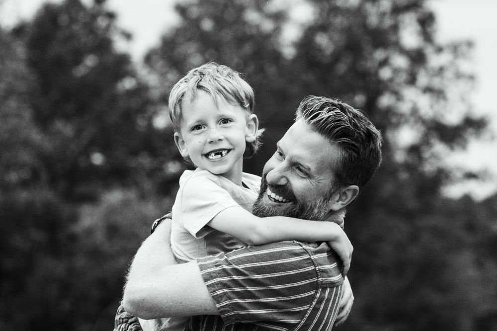 Black and white candid photo of playful moment between parent and child.