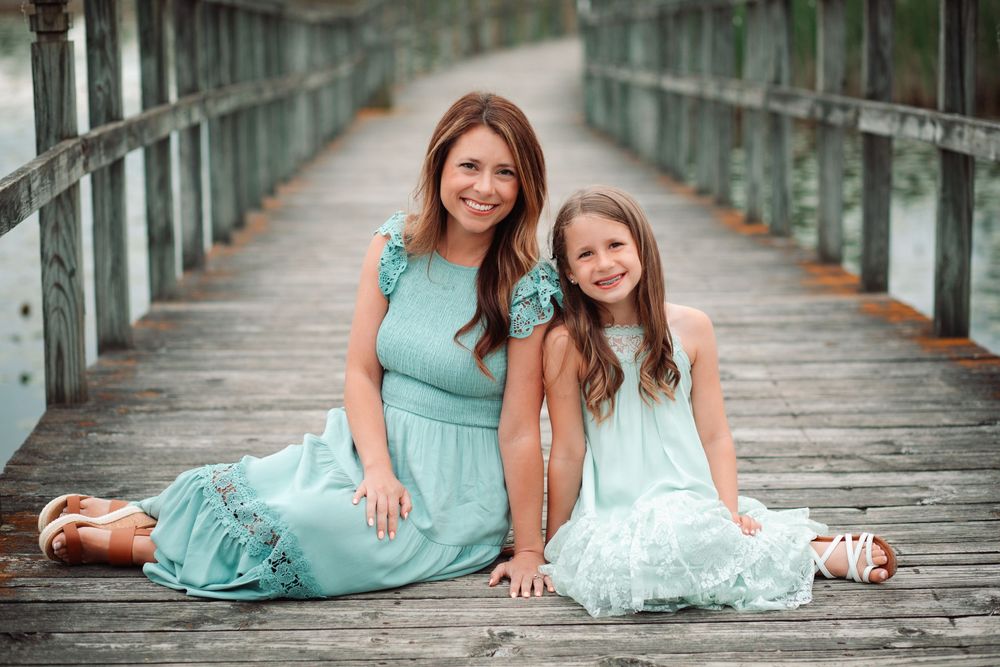 Family members lying on their stomachs on a wooden bridge for a casual outdoor portrait.