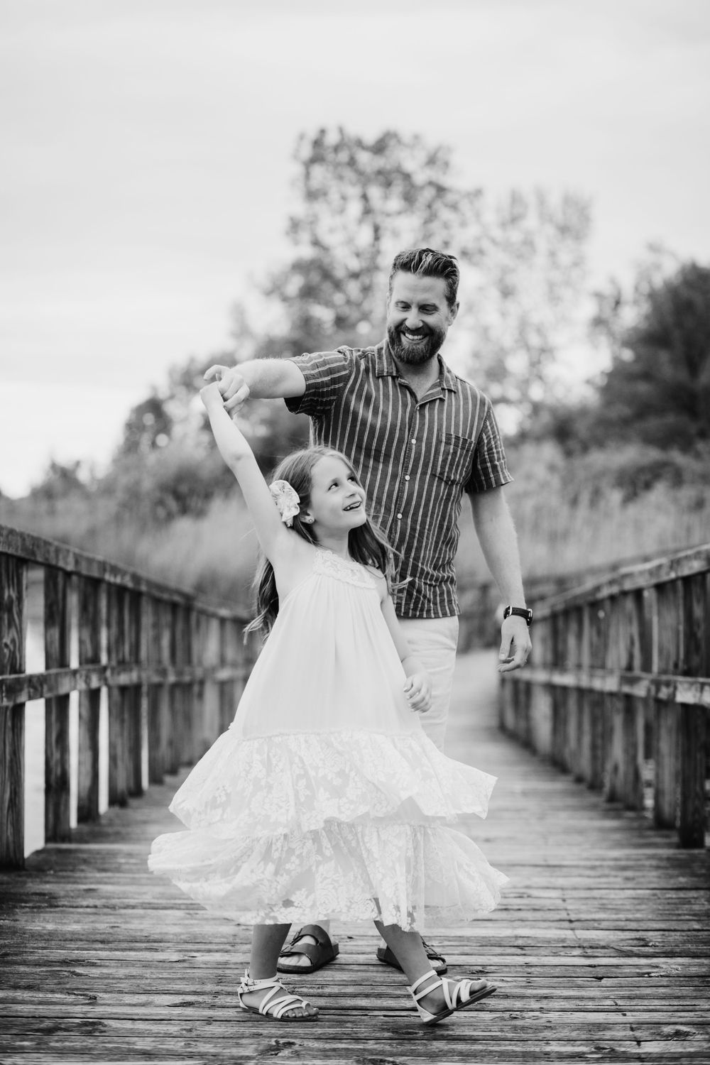 Black and white photo of playful moments on a wooden boardwalk during a family photoshoot.