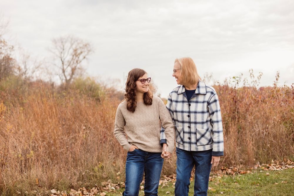 Family group walking together through autumn field with tall grass.