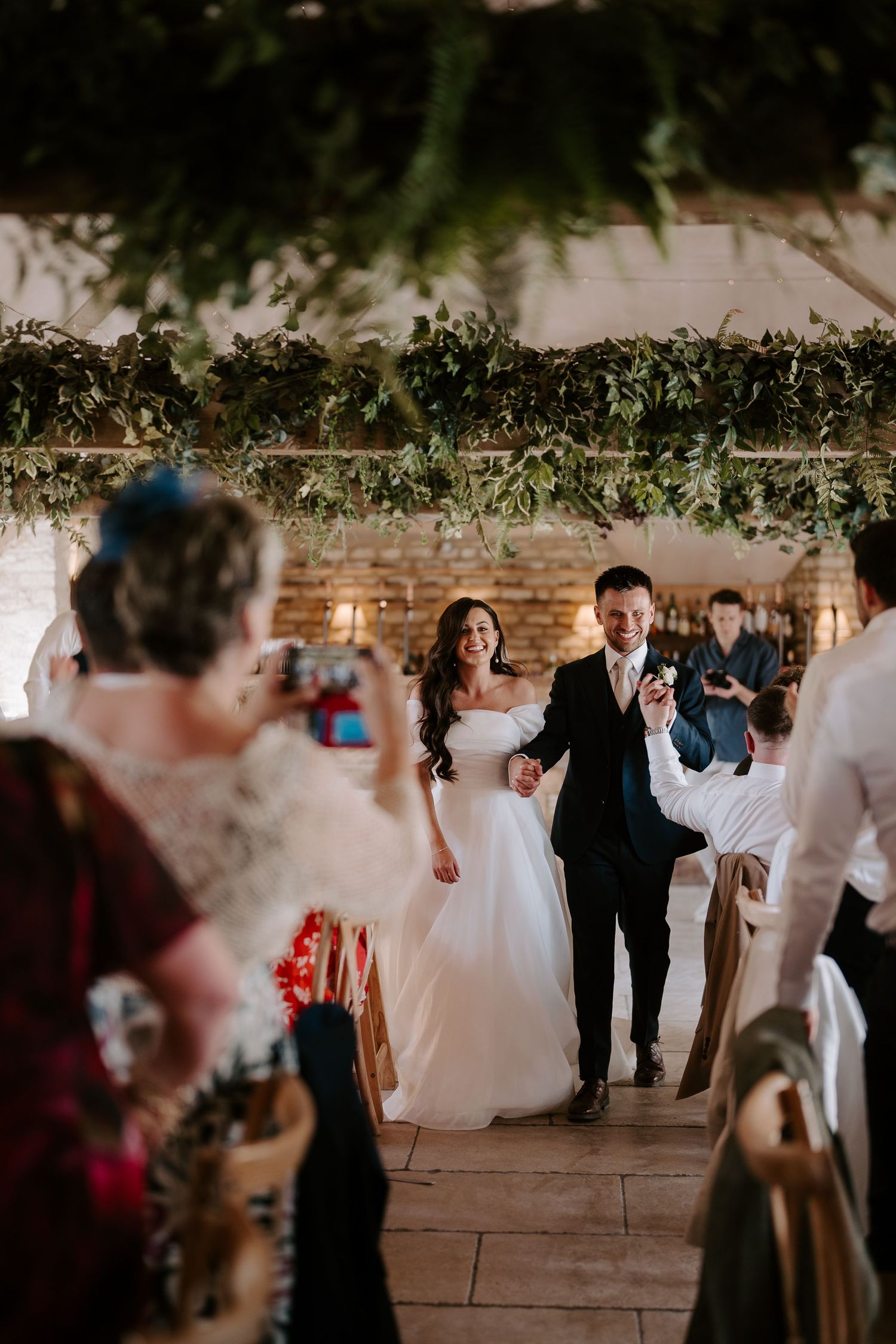 bride and groom entering the wedding breakfast and guests cheering at yardspace old gore cirencester