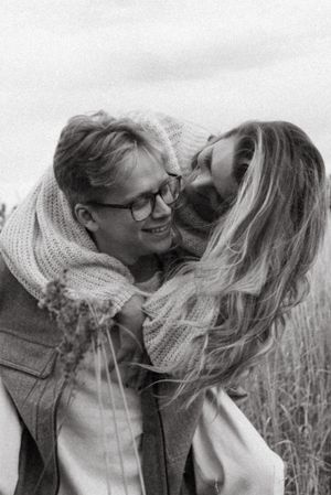 Intimate black and white portrait of couple wearing cozy sweaters in a field.