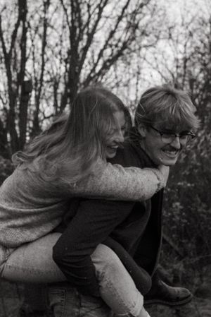 A playful piggyback ride moment captured in black and white among autumn trees.