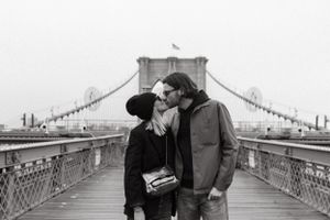 Black and white photo of a romantic moment on Brooklyn Bridge.