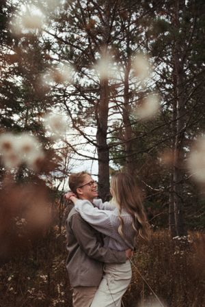 A romantic embrace in a misty forest setting with bokeh light effects in the foreground.