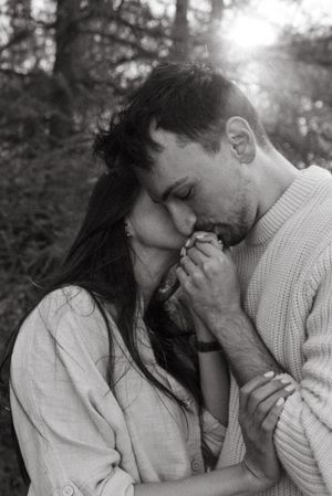 Intimate moment captured between couple holding hands in natural lighting.