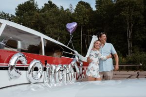 A couple stands by a seaplane with 'Congratulations' written on its window.