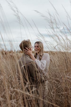 A tender moment captured between two people in a windswept field of wheat.