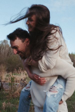 A playful piggyback ride moment captured in warm evening light against a natural backdrop.
