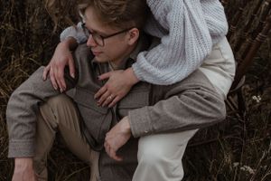 Intimate moment captured between couple sitting in tall autumn grass.