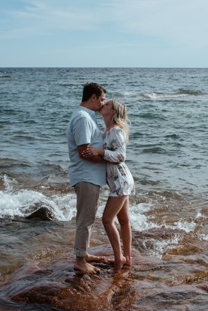 A romantic seaside moment with waves crashing around a couple's feet.