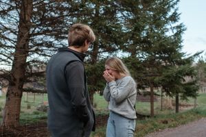An intimate moment shared between two people surrounded by tall pine trees.