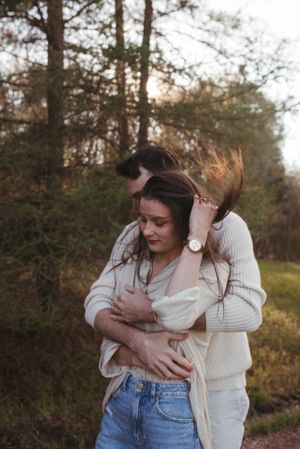Couple in casual attire sharing warm embrace outdoors during golden hour.