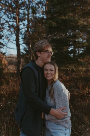 A tender moment between a couple wearing casual attire in a natural outdoor setting.
