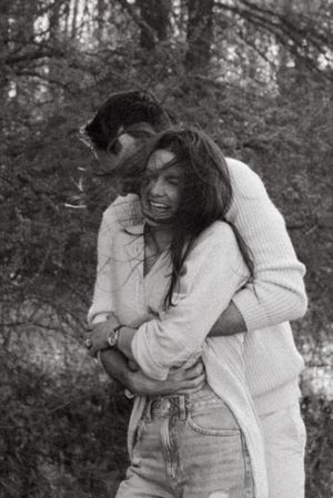 Black and white photo of joyful embrace in forest setting.
