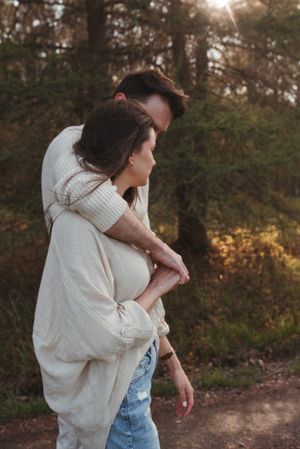 Tender embrace captured in golden sunlight through forest trees.