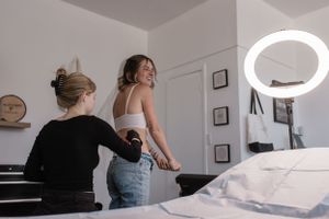 Tattoo artists consulting with client in a minimalist studio setting with ring light fixture.